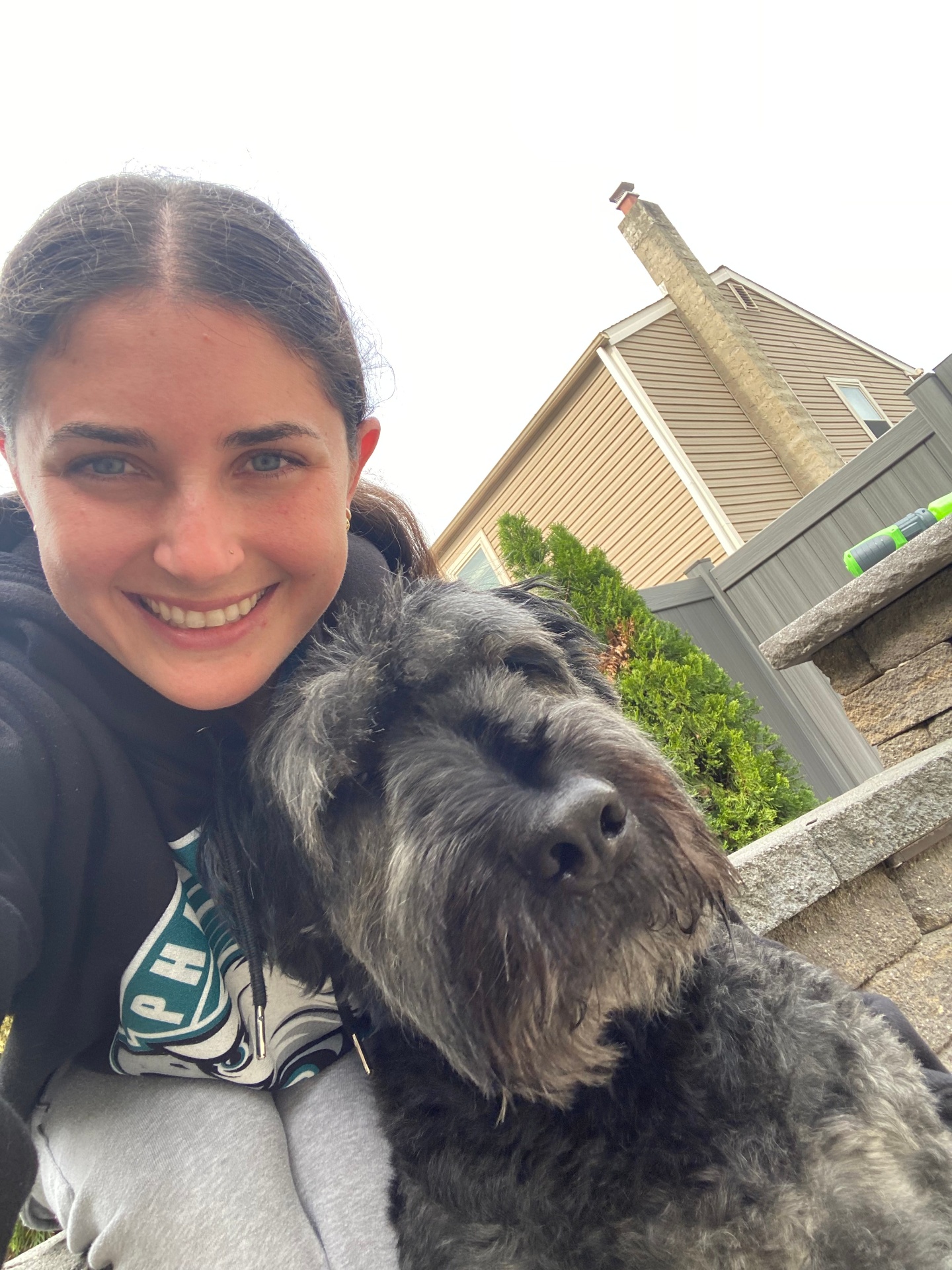 Ally taking a sweet selfie with a fluffy black doodle