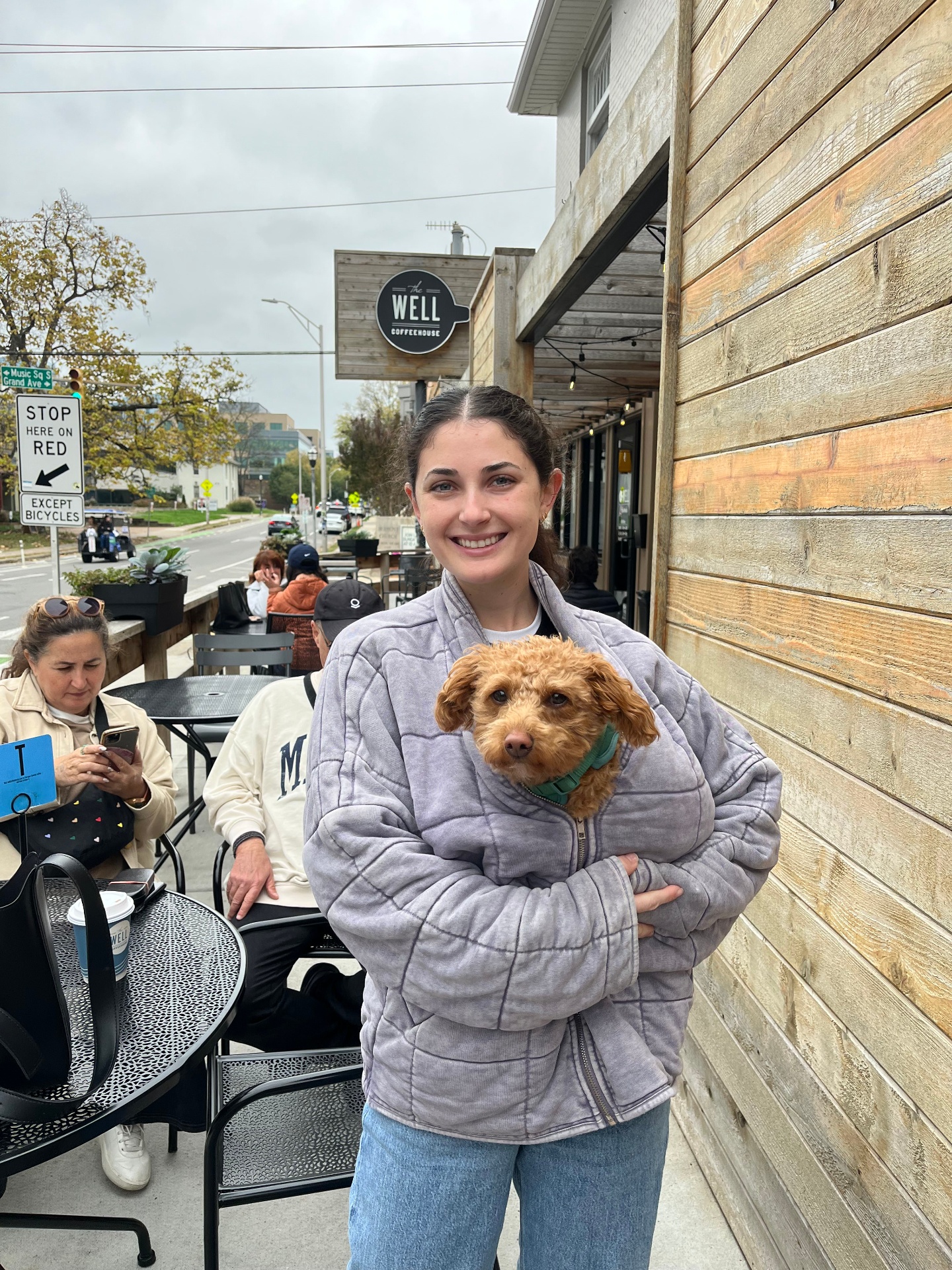 Ally holding a tiny apricot puppy outside a coffee shop