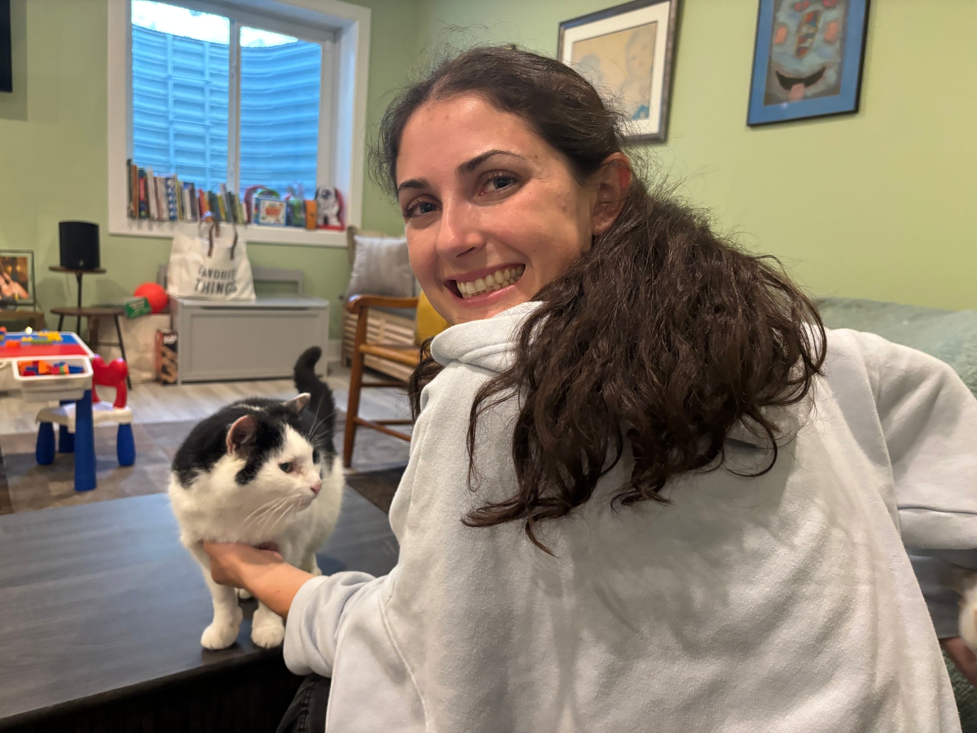 Ally smiling over her shoulder with a black-and-white tuxedo cat